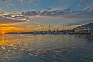 Sunset overlooking Cocoa Village Dentistry Office and the marina at Mariner Square with boats at the dock and a bridge
