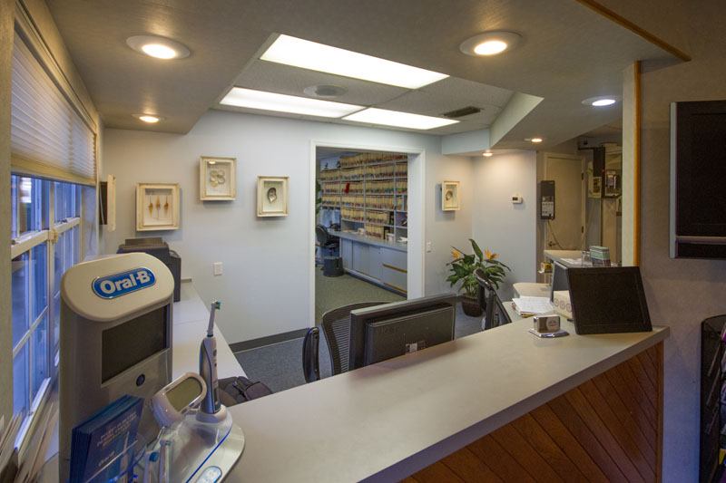 The reception desk at Cocoa Village Dentistry with files neatly shelved, cleared counter space, a TV, and decorations